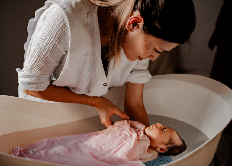 Portrait en couleurs d'une mère baignant son bébé lors d'un rituel du bain sensoriel