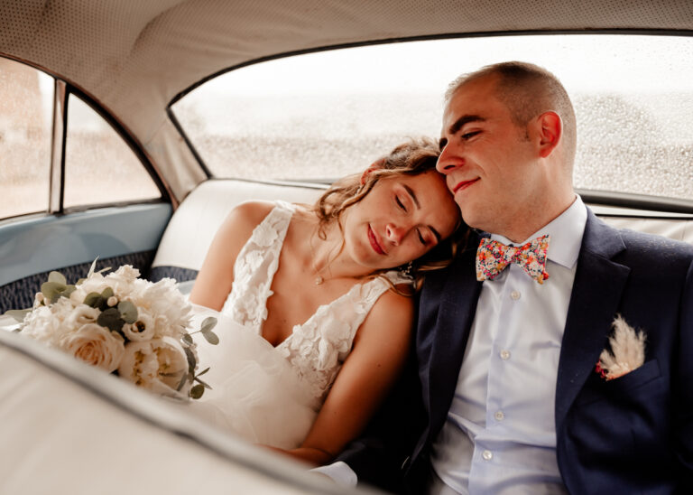 portrait en couleurs d'un couple de mariés, l'un contre l'autre dans la voiture qui les conduit à la mairie