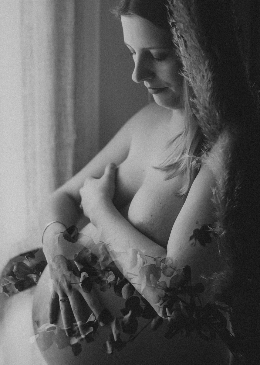 Femme enceinte devant sa fenêtre pendant sa séance photo de grossesse à domicile