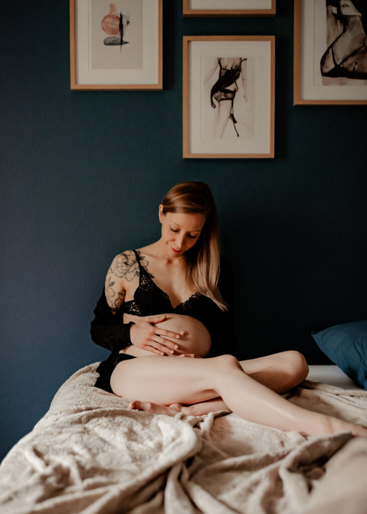 Femme enceinte confortablement installée sur son lit pendant sa séance photo de grossesse à domicile